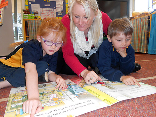 Teacher reading big book with two children.